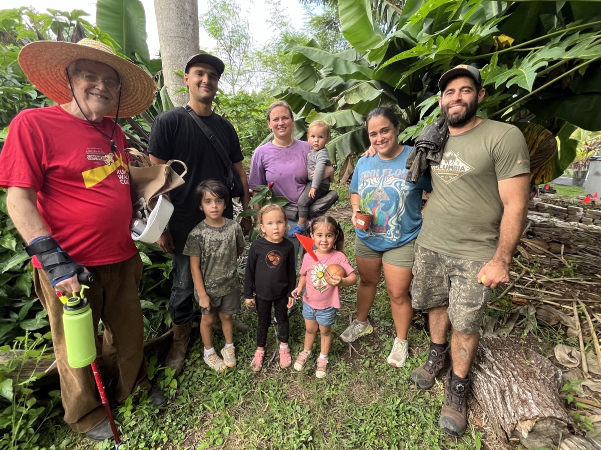 Agroforestry workshop participants and families posing together in the food forest at Fertile Earth