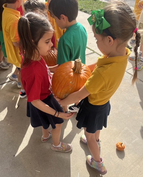 Two Pinecrest Elementary students carrying a pumpkin together